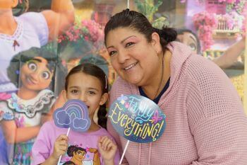Mother and daughter in front of Encanto poster