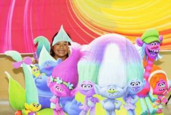 Little girl in front of Trolls Poster