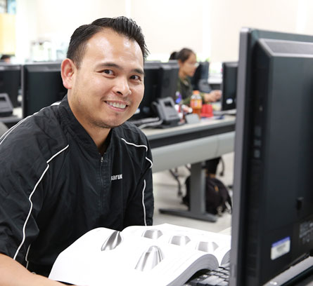 Male student smiling in front of a computer