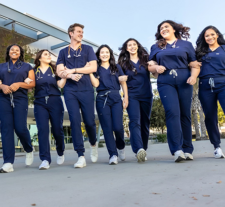 Nursing students happliy walking across campus arm-in-arm