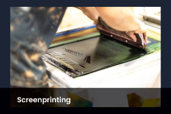 person pulling a black ink on a silk screen frame
