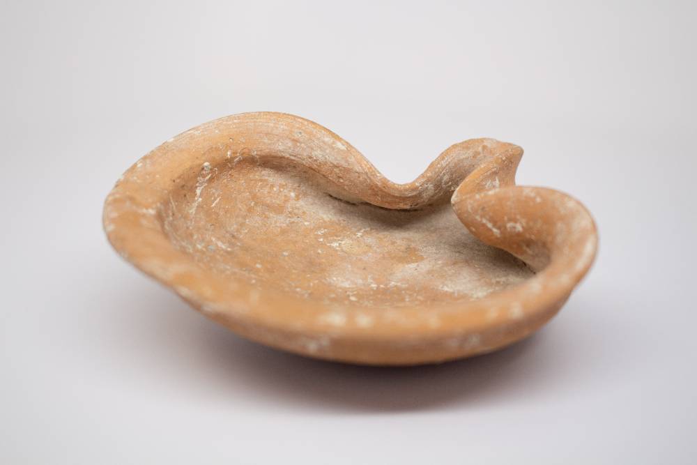 Ceramic oil lamp with shallow discus and pinched rim.