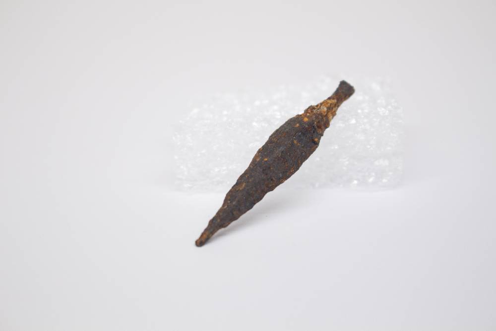 Spindle-shaped tool encrusted in sediment.