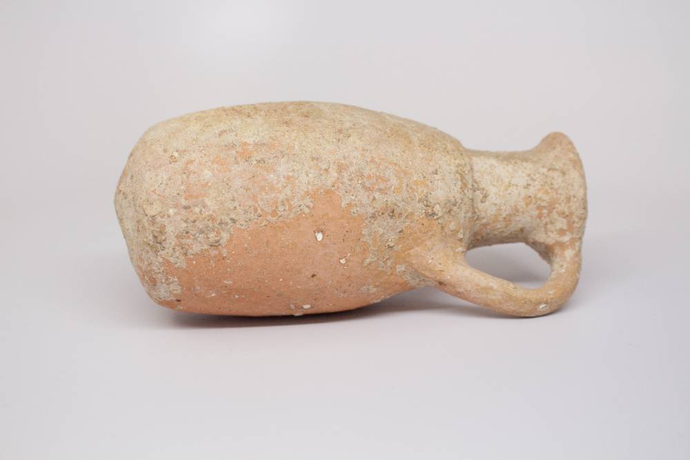 Weathered jug with handle connecting rim and body.