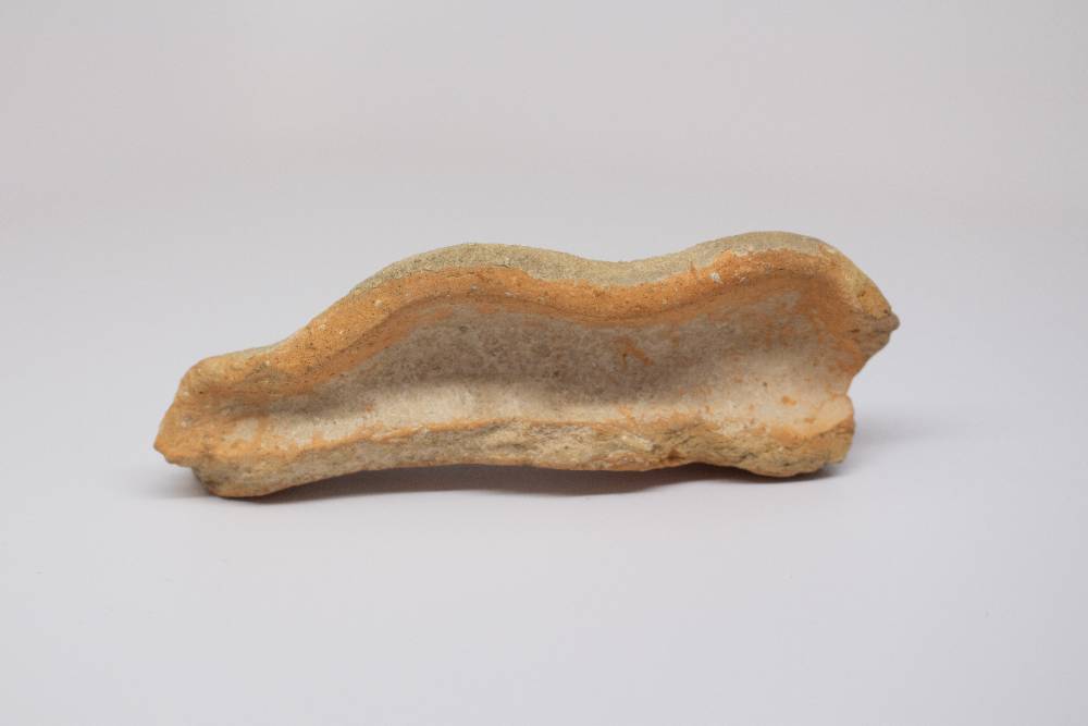 Fragment of ceramic wavy on the top and flat on the bottom.