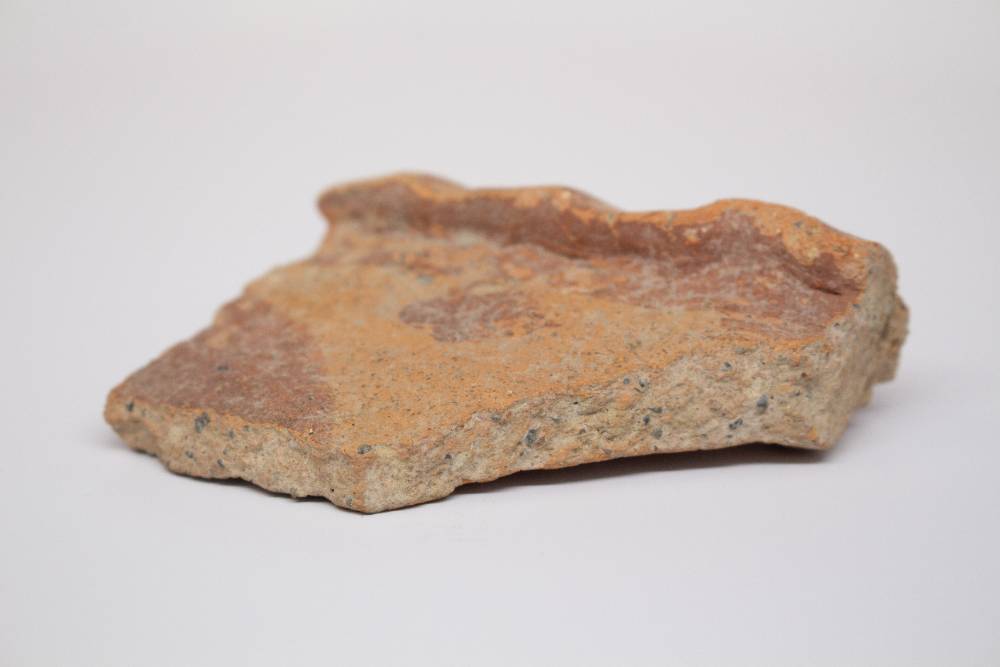 Fragment of ceramic dish that shows part of the portruding rim.