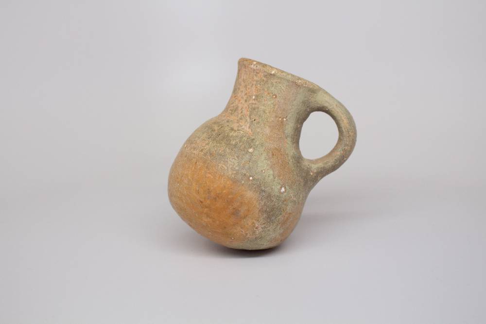 Ceramic jar with a thick neck and a handle connecting the rim and body.