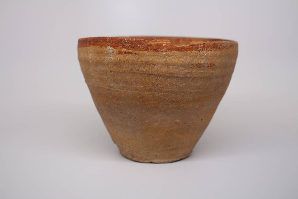Tall conical bowl with burnt-sienna colored rim.