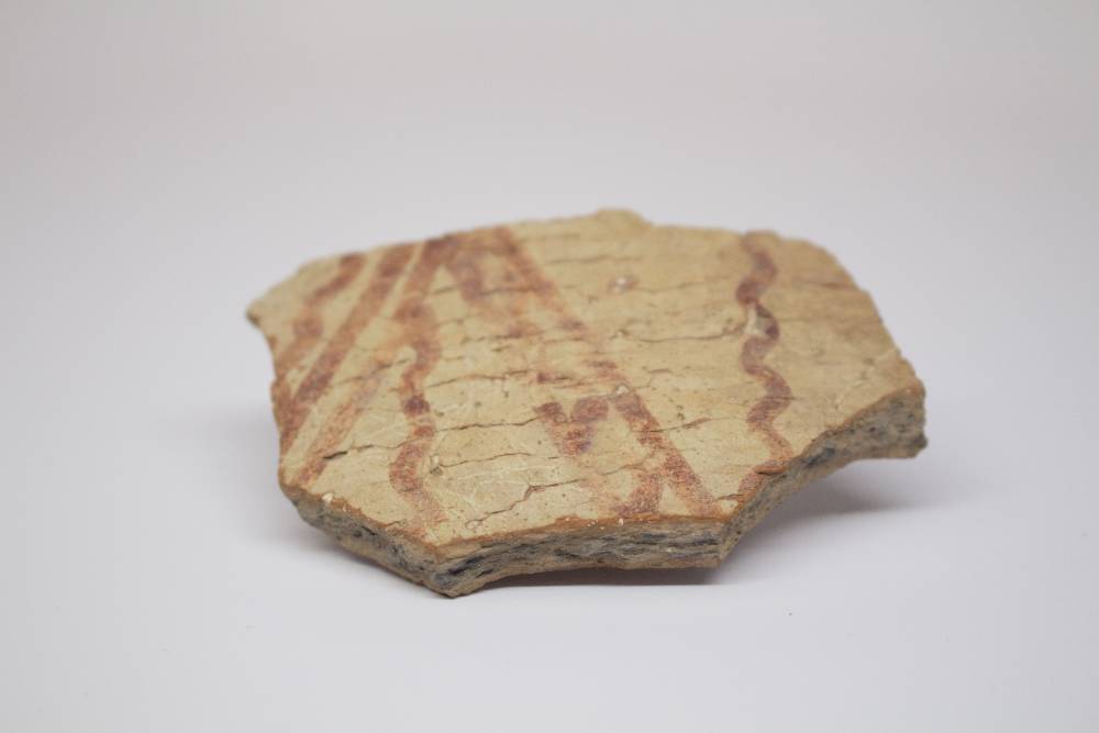 Fragment of ceramic decorated with straight and curved lines.