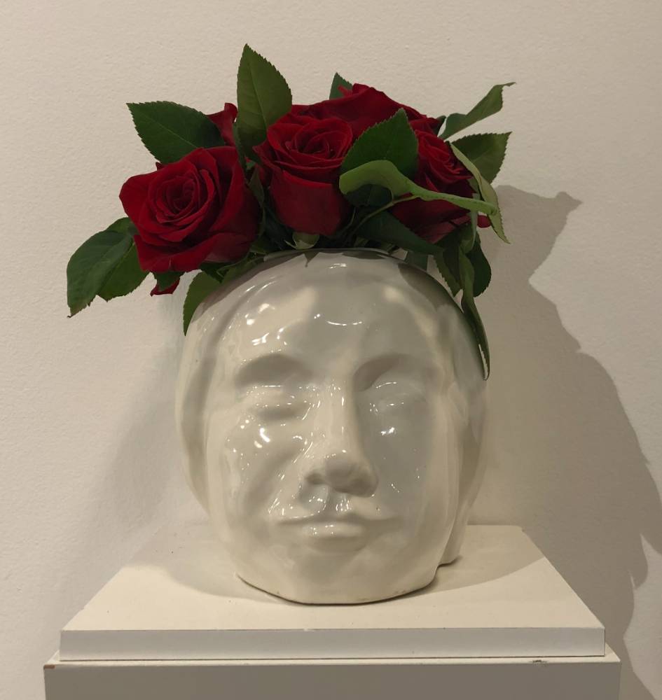 White female head vase with red roses.