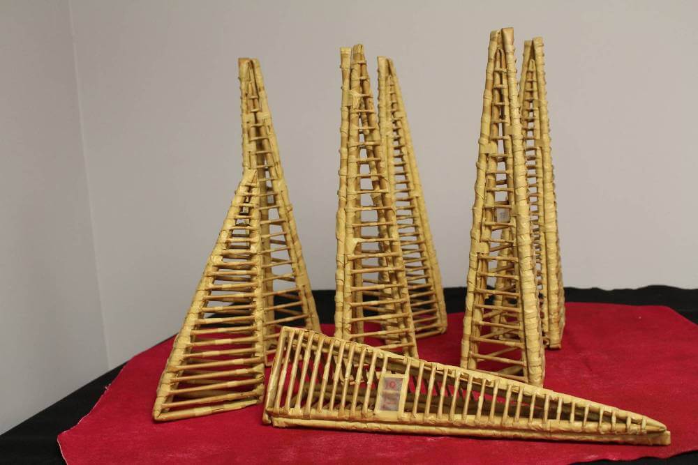 Triangular sculptures made of desaturated yellow-colored paper and tape.