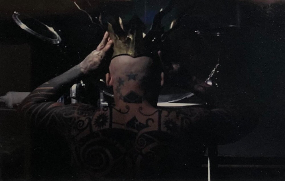 Ron Athey placing gold crown on his head.
