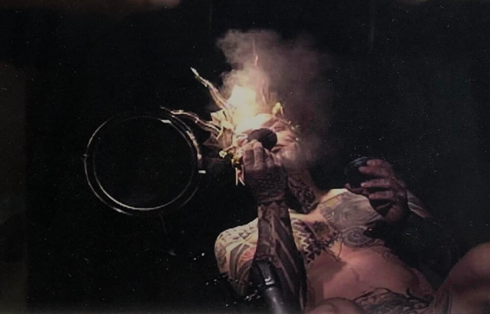 Ron Athey with crown on blowing fire.