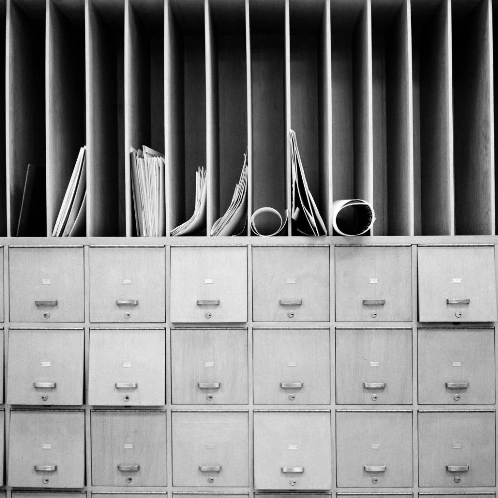 Vertical files with paper inside ontop of 3 by 6 filing cabinet.