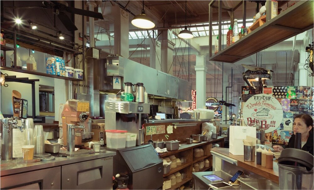 Female customer facing the kitchen area of small restaurant.