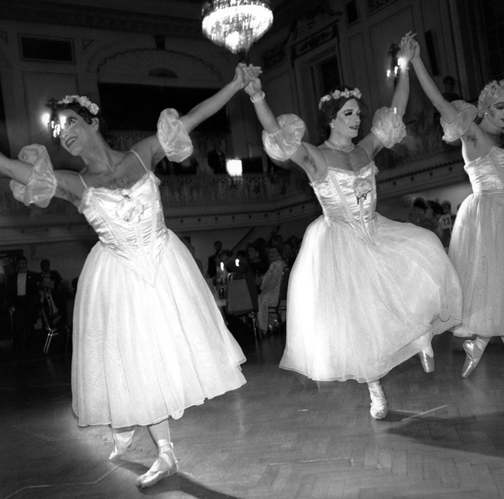 Dancing group Les Ballets Trocadero performing in white women's costumes.