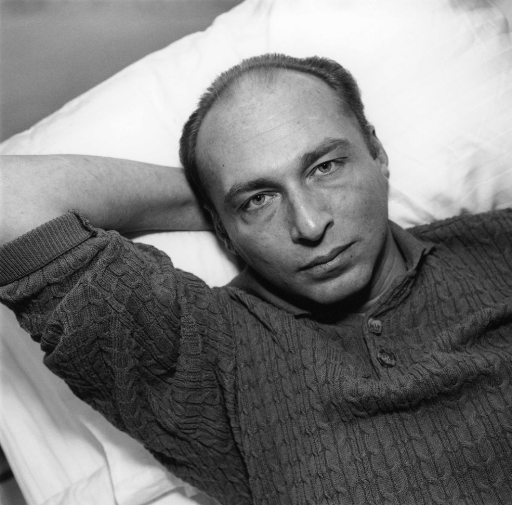 Ron Vawter laying down with arm bent behind his head.