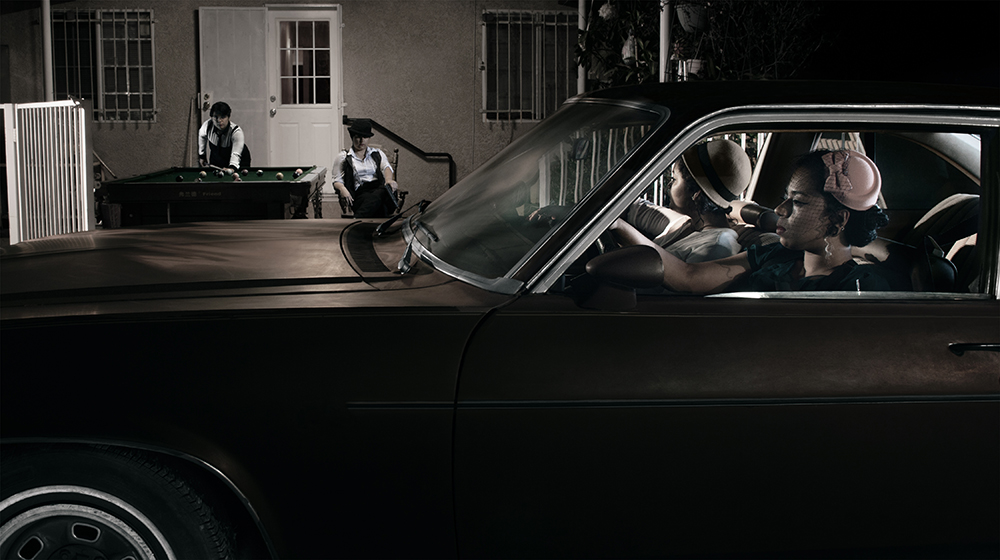 Two women in a car driving up to a house