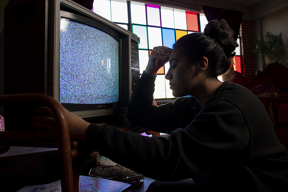 A woman sitting forlorn in front of a blank television