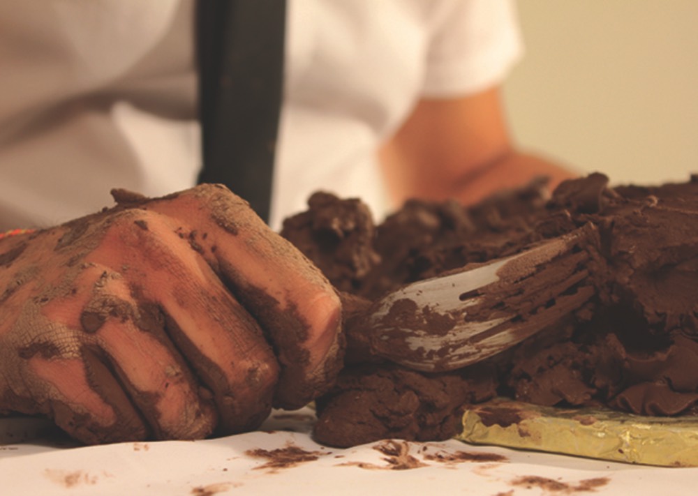 Cake made of mud and a hand holding a fork.
