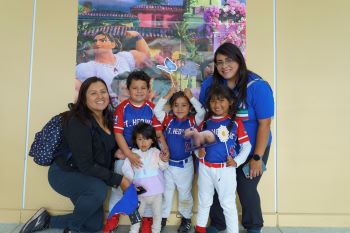 Family in baseball uniforms in front of Encanto poster
