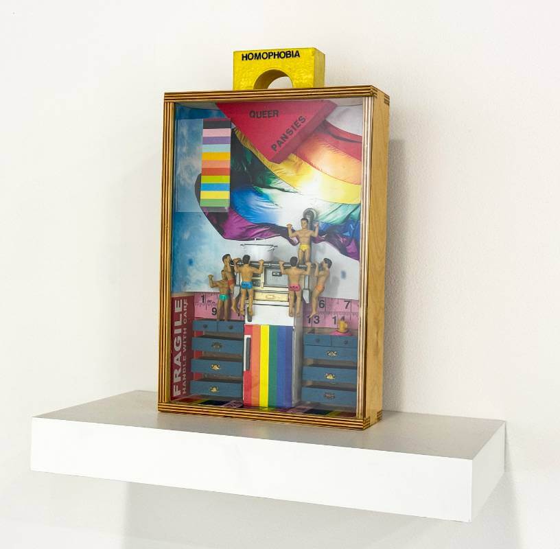 Box with male dolls hanging on edge of stove ontop of rainbow fridge.