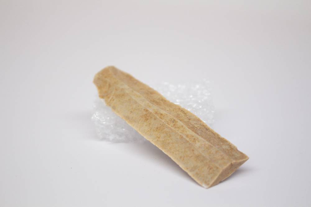 Semi-flat beige tool with depth shaped like an irregular pentagon.