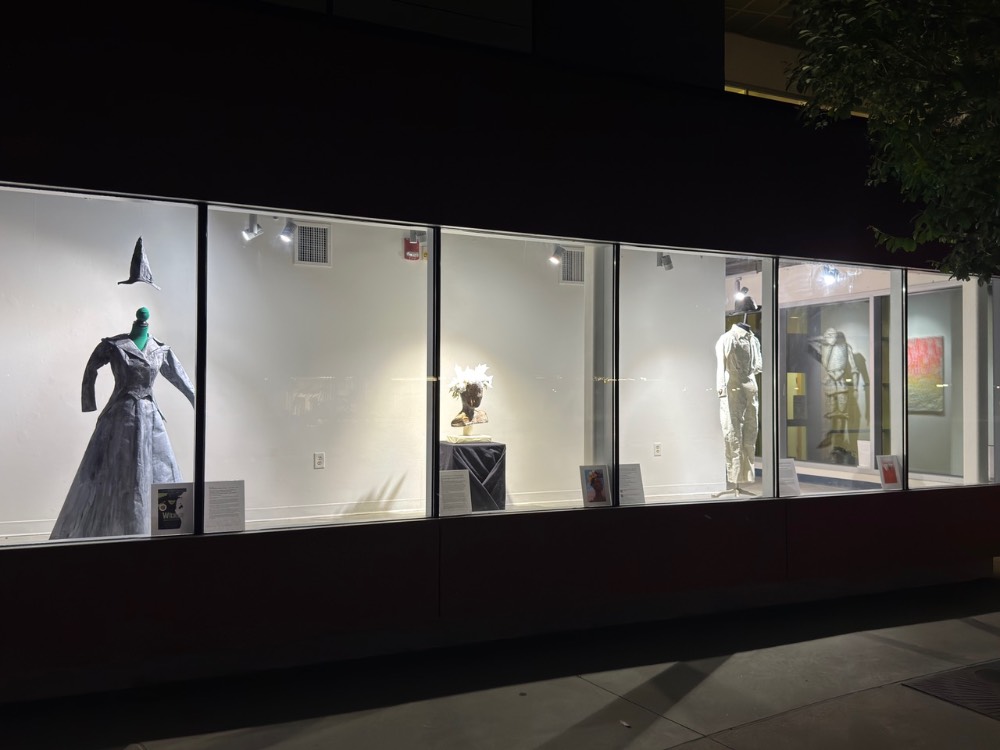 illuminated window with artwork from banned books and paper people