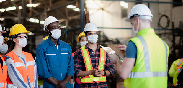 Individuals wearing hard hats and vests working in a warehouse