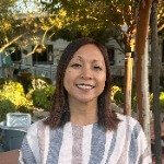 Teacher Rhea's portrait Woman with striped blouse with trees in background