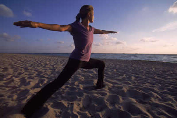 A woman doing yoga on sand