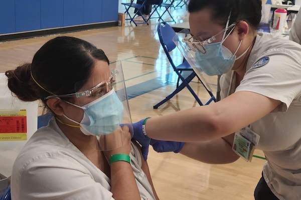 Nursing student giving vaccine to another student