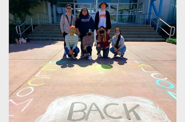 Students with the welcome back chalk message on ground