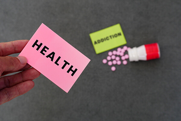 A hand holding health sign with pills and addiction sign