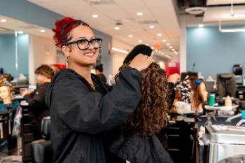 Student working on a hairstyle on a mannequin