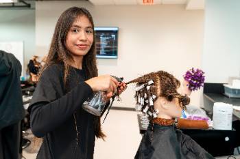 Student working on a hairstyle on a mannequin