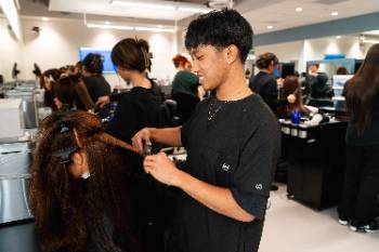 Cosmetology student performing haircut on a mannequin