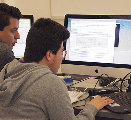 Two students programming on a computer
