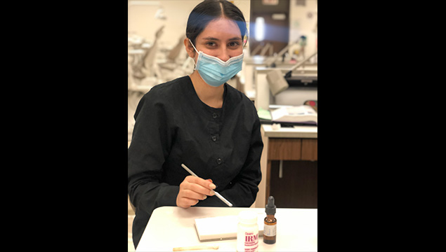 A Dental student smiling with an object in her hand
