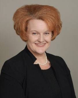 Smiling woman with red hair and black blouse from waist up