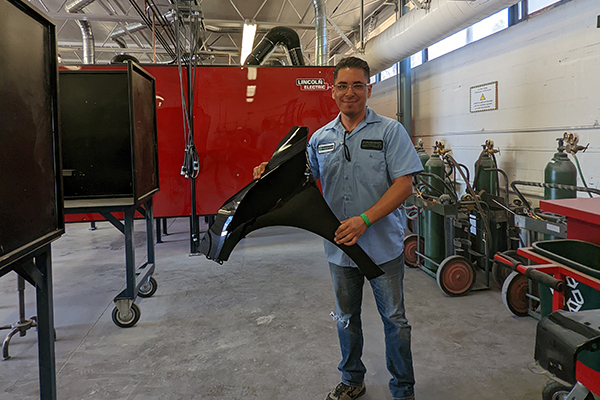 Julio Cano holding an automotive part in a shop