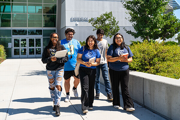 Five students walking on campus