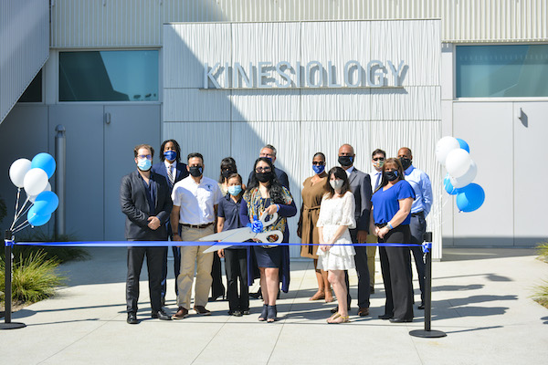 College official cutting ribbon for Health and Wellness Complex completion