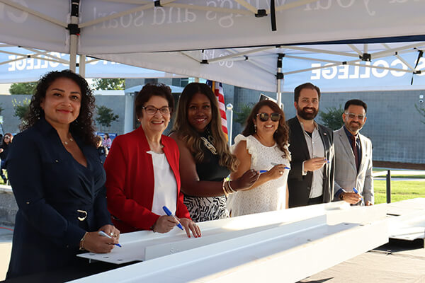 The Board and President signing the beam