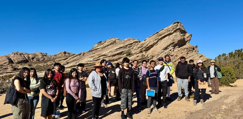 Students standing in front of a rock outcrop.